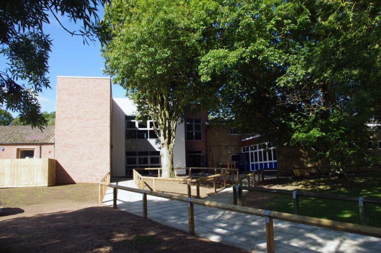 School building framed by mature trees and a planted path