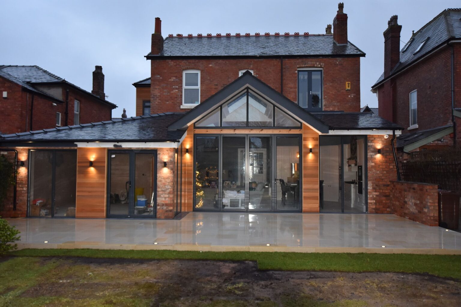 Rear extension at 10 Burlington Road with timber cladding, glazed gable and patio lit at dusk